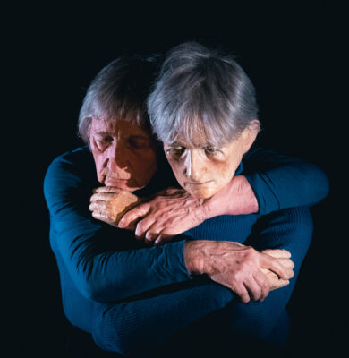 Mime performer emotionally embracing an doll copy of herself.